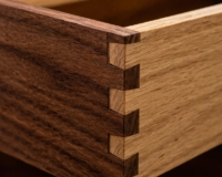 An extreme close-up of the corner of a wooden drawer, clearly showing the interlocking teeth of a dovetail joint.