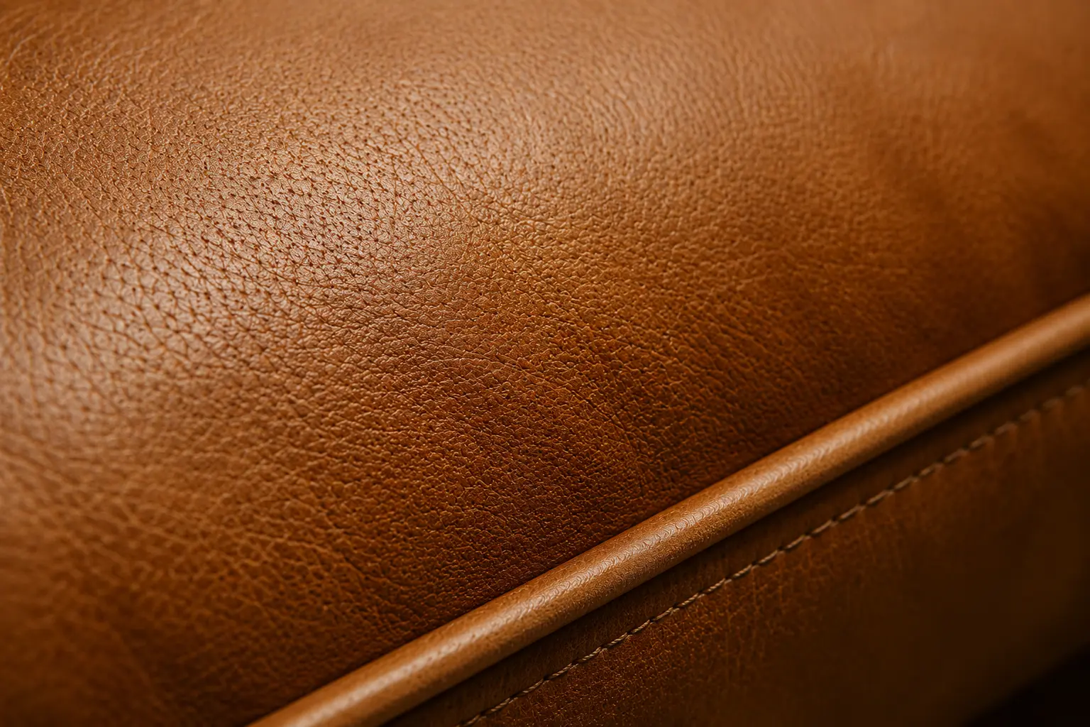 A macro, close-up shot of a tan or cognac premium leather cushion.